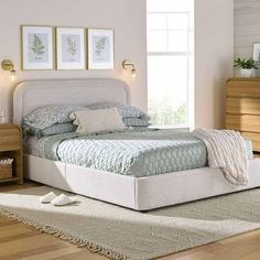 a white bed sitting on top of a wooden floor next to a dresser and mirror