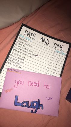 a pink sticky note sitting on top of a bed next to a purple sign that says, date and time you need to laugh