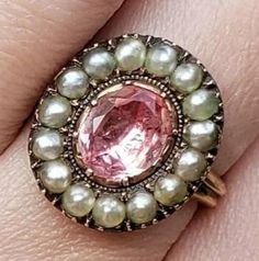 This is one of my most favorite pieces I have ever acquired. It is extremely rare. A perfect example of an exquisite Georgian Imperial Pink Topaz Ring. It's impossible to give an exact carat weight because it is foiled backed as most rings were during this time period. It is a substantial stone (to say the least.) The pink is like none other. Set with sterling silver and yellow gold, the ring is in absolutely pristine condition. I took it to my gemologist and bench worker. All of the seed pearls Antique Pink Rose Cut Diamond Jewelry, Antique Pink Jewelry With Rose Cut Diamonds, Victorian Pearl Ring Gemstone Gift, Victorian Pearl Ring With Gemstone For Gift, Victorian Pearl Ring Gift, Victorian Style Pearl Ring Gift, Antique Pear-shaped Gemstone Jewelry, Antique Pearl Ring With Gemstone, Vintage Pearl Ring With Rose Cut Diamonds For Gift