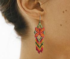 a close up of a woman's ear wearing colorful beaded earrings with flowers