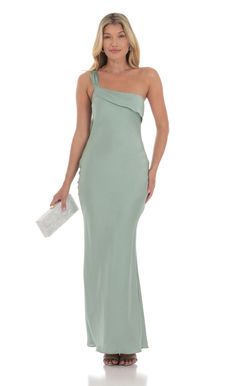 a woman in a long green dress with one shoulder and an open back, posing for the