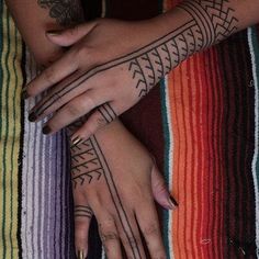 two women with tattoos on their arms and hands are holding each other's hands