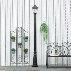 an iron bench and lamppost with potted plants