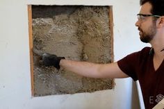 a man in glasses is plastering a wall