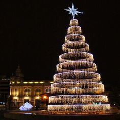 a lit christmas tree in front of a building