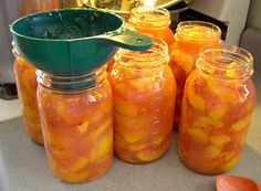 several jars filled with pickles sitting on top of a counter next to oranges