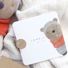 a brown teddy bear wearing a hat and scarf next to a notepad with the name charly on it