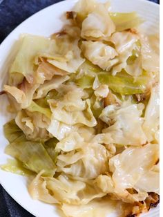 a white plate topped with cabbage covered in gravy on top of a blue table cloth