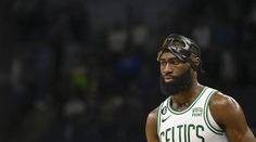 a man with a beard wearing a basketball jersey and head band on his head standing in front of a crowd