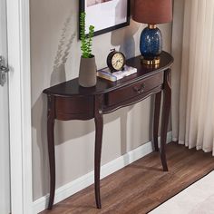 a table with a lamp, clock and vase on it in front of a door