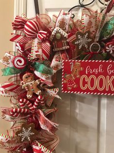 a christmas wreath hanging on the front door decorated with candy canes, cookies and pretzels