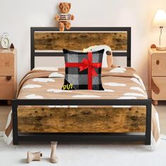 a bed with a teddy bear sitting on it's headboard next to a night stand