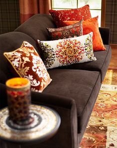 a couch with many pillows on it and a candle in the corner next to it