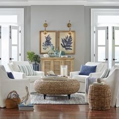 a living room filled with white furniture and blue pillows on top of a wooden floor