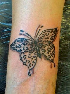 a small tattoo on the wrist of a woman's hand with a black and white butterfly