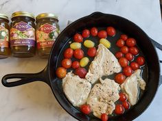 chicken, tomatoes and corn in a skillet with honey on the counter next to it