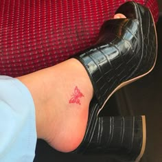 a woman's foot with a small butterfly tattoo on her left ankle, sitting on a couch