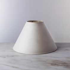 a white lamp shade sitting on top of a table next to a wall and floor