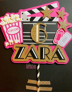 a pink and gold birthday cake topper with popcorn