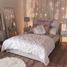 a bed with white sheets and pillows in a room filled with lights on the wall