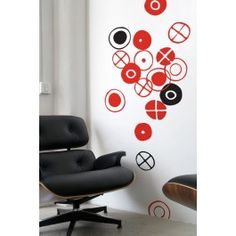 an eames chair and ottoman in front of a wall with red circles on it