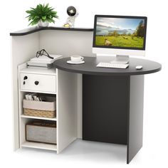 an office desk with a computer monitor and keyboard on it, next to a plant