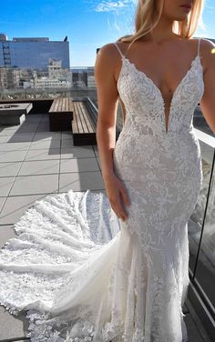 a woman in a white wedding dress standing on a balcony with her back to the camera