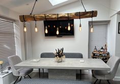 a dining room table with four chairs and a tv mounted above it, hanging from the ceiling