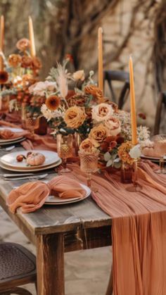 a long table with plates and candles on it is set up for an outdoor dinner