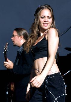 a beautiful young woman standing on top of a stage next to a man holding a guitar