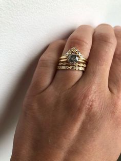 a woman's hand with two gold rings on top of her finger and the ring has a black diamond in it