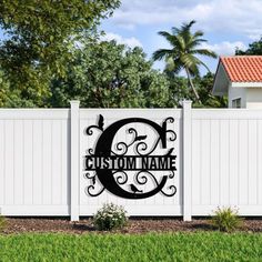 a sign that says custom name in front of a white fence with green grass and trees