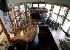 a woman is standing at the counter in a small restaurant with lots of bottles on it