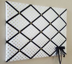 a white wall with gold dots and black ribbon hanging on it's side,