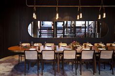 a dining room with a large table and chairs in front of a mirror on the wall