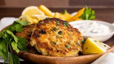 crab cakes with lemon wedges and parsley in a wooden bowl on a table