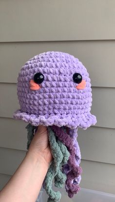 a crocheted octopus hat is being held up by a person's hand