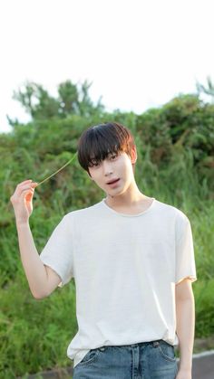 a young man is holding something in one hand and looking at the camera while standing outside