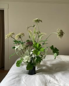 a vase filled with white flowers on top of a bed