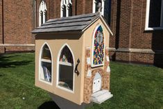 a little church with stained glass windows on the side of it's front lawn