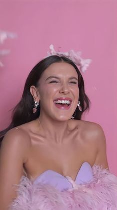 a woman in a pink dress smiling and wearing earrings