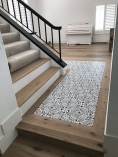 a white and black rug on the floor next to some stairs in an empty room