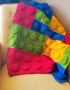 a multicolored blanket sitting on top of a couch next to a white chair