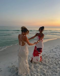 two women standing on the beach holding hands