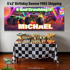 a birthday banner with monster trucks and cupcakes in front of it on a table