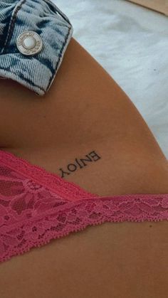 the back of a woman's stomach with a tattoo on her left side that says enjoy