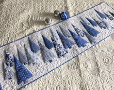 a quilted table runner with blue and white trees on it, surrounded by ornaments