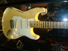 a yellow electric guitar sitting on top of a glass case in front of a wall