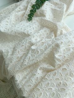 a white dress with green flowers on the top and bottom, sitting on a table