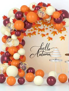 an orange and white fall themed arch with balloons in the shape of leaves, acorns and berries